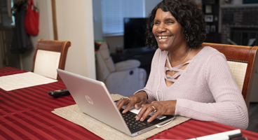 A blind woman smiles while listening to a meeting on her computer.
